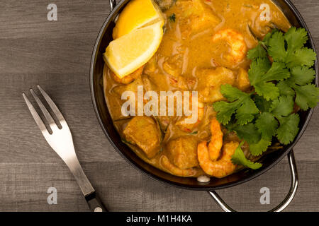 Sri Lanka Style King Prawn Curry mit Zitrone und Koriander Kräuter auf einem dunklen, hölzernen Tischplatte Stockfoto