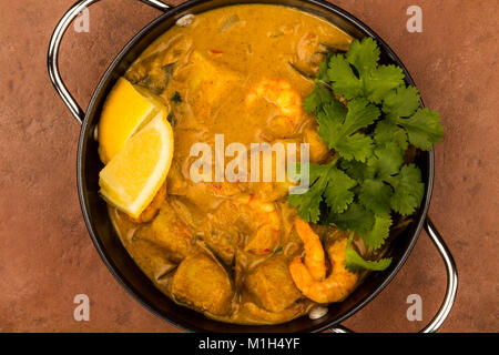 Sri Lanka Style King Prawn Curry mit Zitrone und Koriander Kräuter gegen einen roten Fliesen- Hintergrund Stockfoto