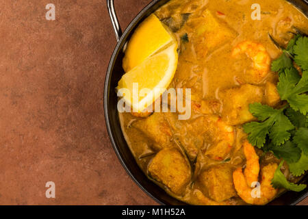 Sri Lanka Style King Prawn Curry mit Zitrone und Koriander Kräuter gegen einen roten Fliesen- Hintergrund Stockfoto