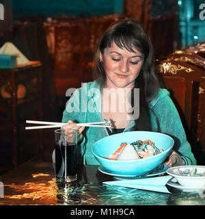 Junge Frau genießt ihre Mahlzeit im asiatischen Restaurant Stockfoto