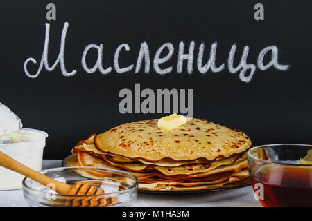 Die Inschrift auf einer Schiefertafel auf Russisch: maslenitsa. Traditionelle ukrainische oder russische Pfannkuchen. Traditionelle Gerichte auf den Urlaub Karneval Maslenit Stockfoto