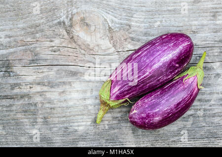 Zwei reife lila Auberginen auf den alten grauen Holzbrett Stockfoto