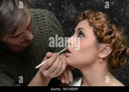 Stylist gilt, Make-up, ein Modell, das sich auf abstrakten Hintergrund Stockfoto