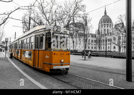 Ein Bild von den typischen gelben Straßenbahn in Budapest, Ungarn. Die Straßenbahn befindet sich in der Schwarzen und weißen Hintergrund isoliert. Das ungarische Parlament hinter. Stockfoto