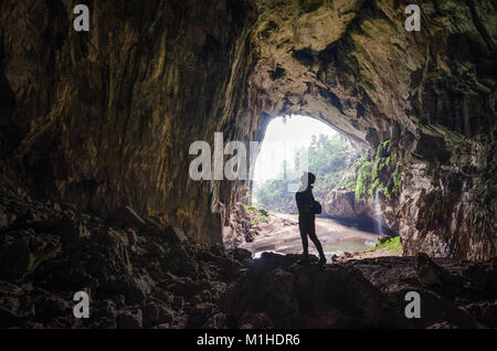 Schöne Silhouette eines Mädchens mit den herrlichen Hang en Höhleneingang im Hintergrund Stockfoto