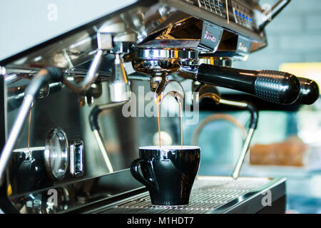 Golden espresso tropft vom portafilter in einem modernen Coffee Shop Stockfoto