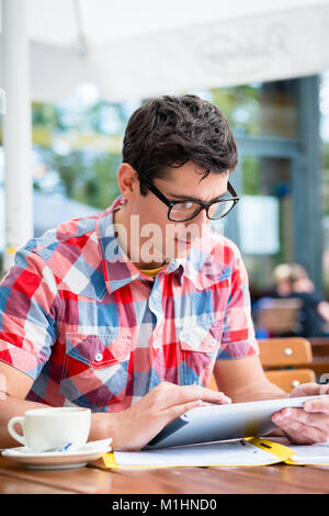 Man trinkt Kaffee in Street Cafe Lesung am tablet device Stockfoto