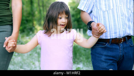 Schöne Mädchen mit Down-Syndrom zu Fuß mit den Eltern Stockfoto