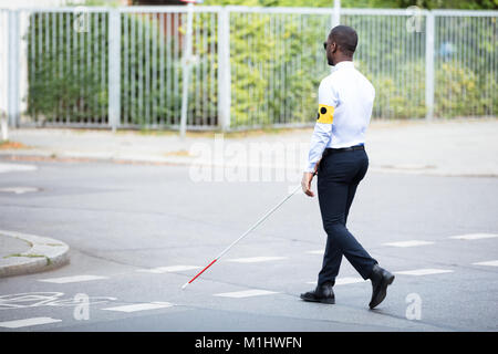 Junge afrikanische blinden Mann, Armband mit Stick überfahrt-Straße Stockfoto