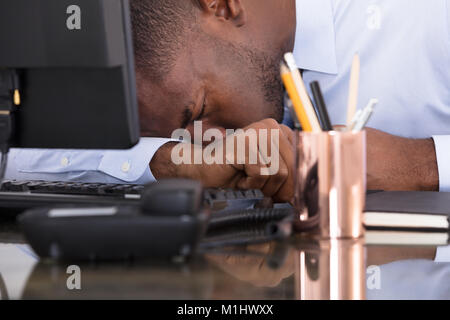 Nahaufnahme einer Müde Geschäftsmann mit dem Kopf nach unten auf Schreibtisch Stockfoto