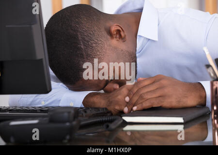 Nahaufnahme einer Müde Geschäftsmann mit dem Kopf nach unten auf Schreibtisch Stockfoto