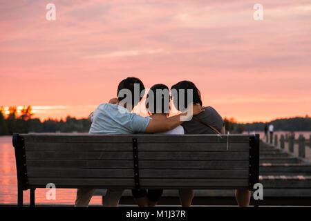 Menschen, die auf einer Bank sitzen genießen den Sonnenuntergang am Muskoka Wharf in Gravenhurst MUSKOKA, Ontario, Kanada. Stockfoto