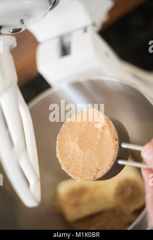 Hinzufügen von brauner Zucker Butter in Silber Schüssel zu einem stand Mixer angeschlossen Stockfoto