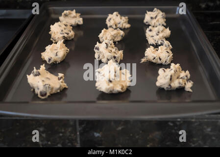 Frische hausgemachte Chocolate Chip Cookie Teig auf schwarz Plätzchenblatt bereit, in den Ofen zum Backen platziert werden Stockfoto