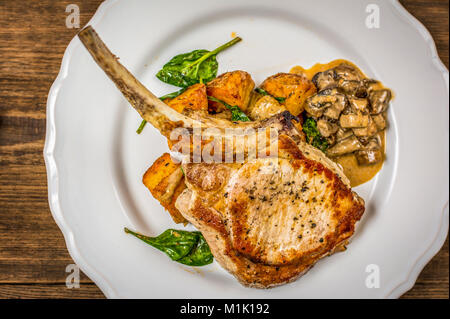 Gebackene Schnitzel oder Kotelett mit Pilzsauce und Kartoffeln mit Spinat Top View Stockfoto