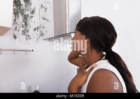 Nahaufnahme einer Schockiert afrikanische Frau auf der Suche nach Schimmel an der Wand Stockfoto