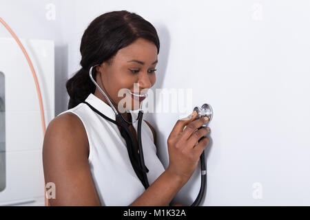 Nahaufnahme einer jungen afrikanischen Frau Inverkehrbringen Stethoskop an der Wand Stockfoto