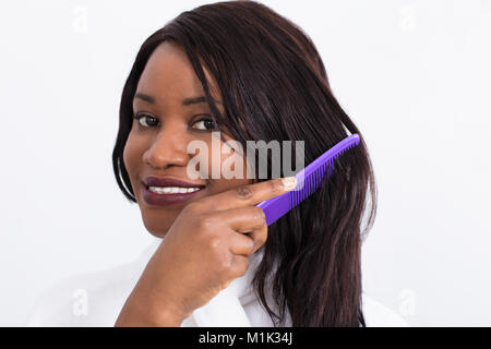 Portrait einer jungen afrikanischen Frau ihre Haare kämmen Stockfoto