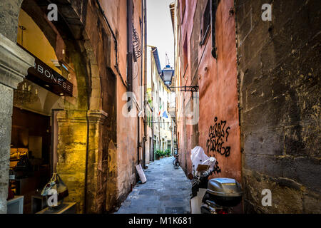 Eine schmale Gasse mit Geschäften, Motorroller und Fahrräder in der toskanischen Stadt von Pisa Italien Stockfoto