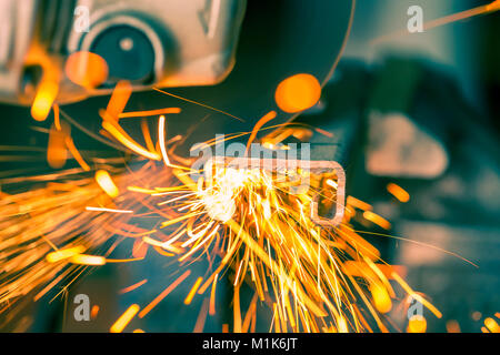 Orange Funken fliegen aus Metall mit elektrischer Grinder, Stockfoto