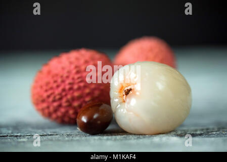 Drei lychee Früchte und Samen auf Holz- Hintergrund Stockfoto