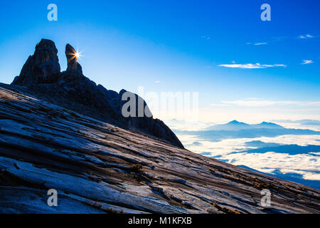 Früh, als die Sonne Altersgenossen aus hinter den Eselsohren Peak auf dem Mount Kinabalu in Sabah Borneo Stockfoto