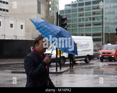 London, UK, 31. Januar 2018, ein Mann mit einem kleinen Schirm, um zu versuchen, die Schwere Unwetter Regen in Victoria London © Keith Larby/Alamy Leben Nachrichten vermeiden Stockfoto