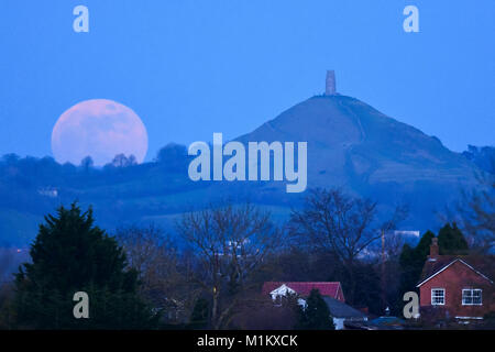 Glastonbury, Somerset, UK. 31. Januar 2018. UK Wetter. Die Super blaues Blut Mond aufgehend von hinter dem Glastonbury Tor in Somerset in der Abenddämmerung. Foto: Graham Jagd-/Alamy Leben Nachrichten. Stockfoto