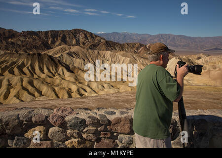 Death Valley, Kalifornien, USA. 12. März 2016. Ein Fotograf der Badlands am Zabriskie Point. Zabriskie Point ist ein Teil des Amargosa Bereich östlich von Death Valley und ist bekannt für seine erosive Landschaft. Death Valley National Park in den US-Bundesstaaten Kalifornien und Nevada, östlich der Sierra Nevada, besetzen eine Schnittstelle-Zone zwischen der trockenen Great Basin und Mojave Wüsten. Der Park enthält eine Wüste Vielfalt des Salz-Wohnungen, Sanddünen, Badlands, Täler, Schluchten und Berge. In diesem unten Meeresspiegel Becken Sommer stetigen Dürre und Datensatz Hitze machen Death Valley ein Land der Stockfoto