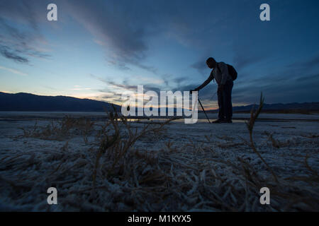 Death Valley, Kalifornien, USA. 12. März 2016. Ein Fotograf schießt den Sonnenuntergang auf Baumwolle Ball Becken Salzsee Badwater Basin im Death Valley National Park in der Nähe. Der Park enthält eine Wüste Vielfalt des Salz-Wohnungen, Sanddünen, Badlands, Täler, Schluchten und Berge. In diesem unten Meeresspiegel Becken Sommer stetigen Dürre und Datensatz Hitze machen Death Valley ein Land der Extreme. Dennoch hat jede Extreme einen eindrucksvollen Kontrast. Aufragende Gipfeln sind mit Schnee bereift. Seltene Regenfälle bringen weite Felder von Wildblumen. Üppige Oasen beherbergen kleine Fische und Zuflucht für Tiere und Menschen. De Stockfoto