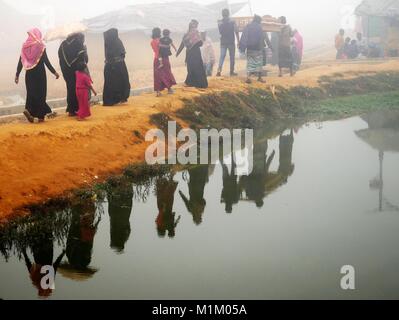 Januar 16, 2018 - Cox's Bazar, Bangladesch - Rohingya-flüchtlinge gesehen zu Fuß neben einem Pfund an der Kutupalong Flüchtlingslager. Sogar Papst Franziskus nicht erlaubt wurde, ein Wort ''''Rohingya in Myanmar zu sagen. Mehr als eine Million Rohingya Flüchtlinge, die im August 2017 floh aus Rakhine State in Myanmar gezwungen waren, ihr Leben zu retten von ethnischen Säuberungen leben in sehr einfachen Bedingungen in den Flüchtlingslagern in Bangladesch und ihre Zukunft ist sehr unsicher. Sie haben Angst, nach Hause zurückzukehren - aber Rückführung Vertrag wurde bereits unterzeichnet, sie zur Rückkehr in ihre Heimat, wo sie nicht erwünscht sind. (Credit Stockfoto