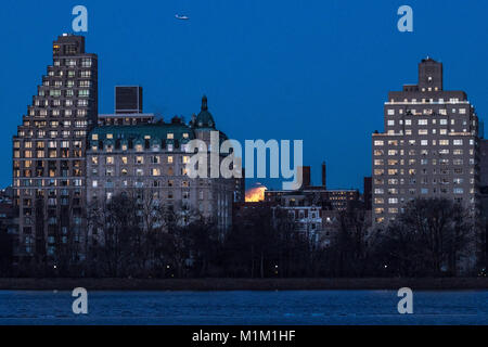 New York, USA. 31 Jan, 2018. Ein Hubschrauber überfliegt, wie eine Mondfinsternis über New York City's Upper West Side früh am 31. Januar 2018 zu sehen ist. Ein seltener Zufall, der einen blauen Mond, supermoon und Mondfinsternis wird ein "Blut" Mond - ein Ereignis, das nicht in mehr als 150 Jahren geschehen ist. Credit: Enrique Ufer/Alamy leben Nachrichten Stockfoto