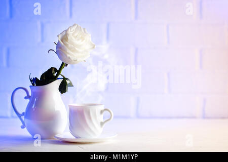 Sanfte weiße Rose in einer Vase und eine Tasse Kaffee.. Hintergrund mit kopieren. Stockfoto
