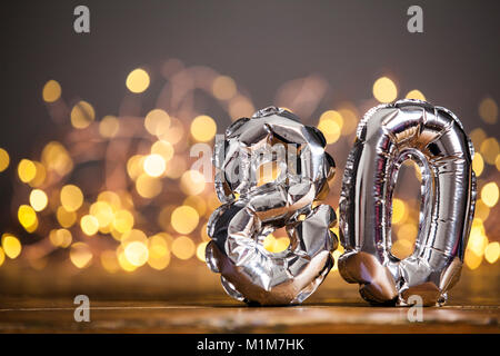 Silber Anzahl 80 Feier Folien Ballon gegen Licht Hintergrund verschwommen Stockfoto