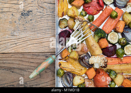 Gebratenes Gemüse in ein Backblech mit einem Vintage Spachtel auf Holz Hintergrund Stockfoto