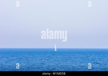 Kleines Segelboot am Horizont auf offener See. Stockfoto