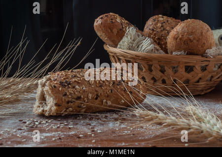 Frisches Brot mit verschiedenen Samen auf rustikalen Holzmöbeln Hintergrund Stockfoto