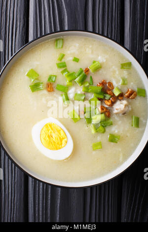 Arroz Caldo Suppe mit Reis, Huhn und Ei close-up in eine Schüssel. Senkrechte Draufsicht von oben Stockfoto