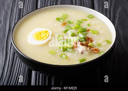 Hot Arroz Caldo traditionelle Reissuppe mit Huhn, Gemüse und Ei close-up in einer Schüssel auf dem Tisch. Horizontale Stockfoto