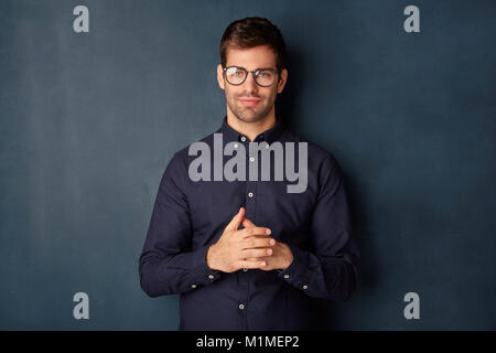 Portrait von lächelnden jungen Geschäftsmann mit Brillen von der Kamera, während gegen bei dunklem Hintergrund stehend mit kopieren. Stockfoto