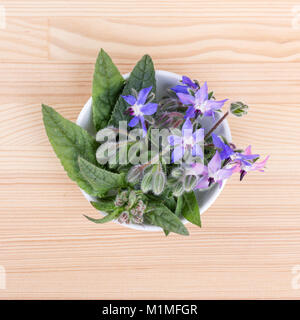 Blick von oben auf eine Schüssel mit Borretsch auf einem Holzbrett Stockfoto