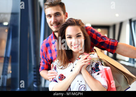 Verkauf, Konsumismus und Personen Konzept - glückliches junges Paar mit Einkaufstaschen wandern in der Mall. Stockfoto