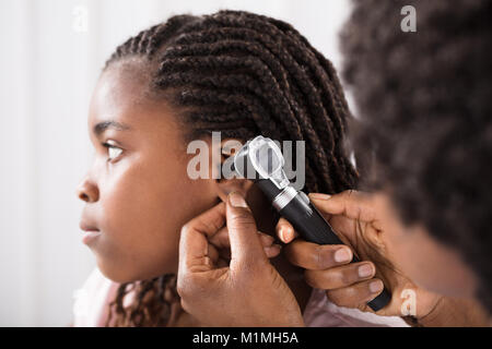 Arzt mit otoskop Instrument Girl's Ohr im Krankenhaus zu prüfen. Stockfoto