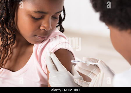 Arzt Anwendung Injektion zu afrikanischen Mädchen in der Klinik Stockfoto