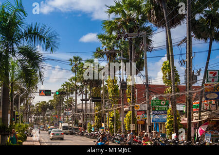 Eine typische Straße in der Kata mit einer Menge Motorräder parken am Straßenrand unter einer Reihe von Palmen und Utility Pole. Stockfoto