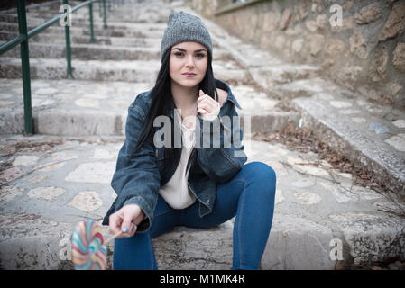 Porträt einer Frau sitzt auf der Treppe Holding einen Lutscher Stockfoto