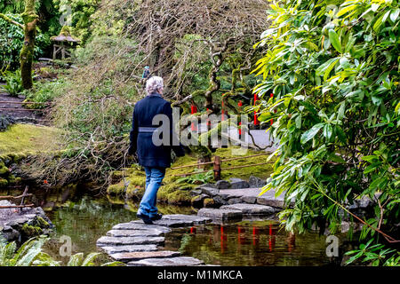 Frau gehen über Trittsteine, die in einem Teich Stockfoto