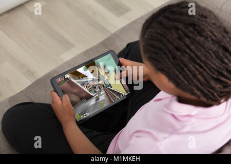 Erhöhten Blick auf ein Mädchen sitzen auf der Couch spielen Video Game auf digitalen Tablet Stockfoto