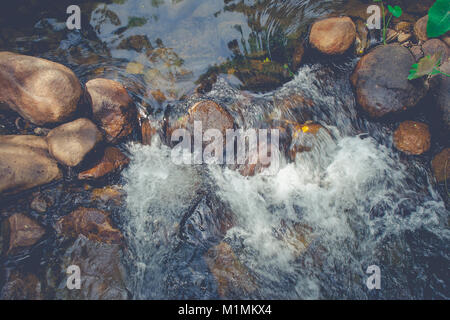 Ansicht von oben schöne kleiner Wasserfall in den Fluss mit Wasser Strom fließt durch Stein mit grünen Bäumen umgeben. Stockfoto