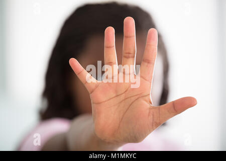 Mädchen machen Stop-Schild auf defokussiertem Hintergrund Stockfoto